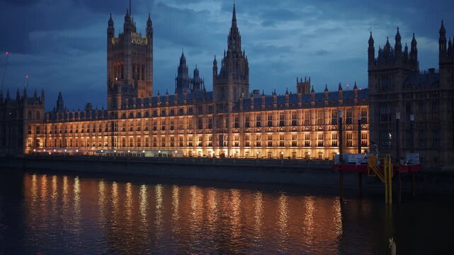 View of the Palace of Westminster at night with its lights reflecting on the River Thames, London, England