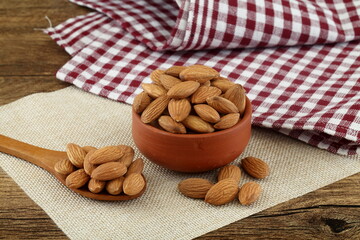 Close up of fresh almonds spilled out of wooden bowl