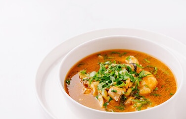 Delicious seafood soup with fresh herbs served in a white bowl
