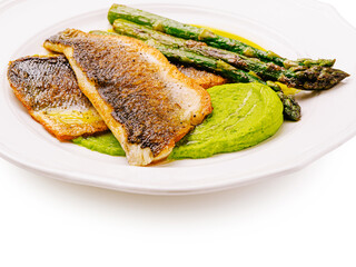 Delicious fish fillet served with asparagus and pea puree on plate