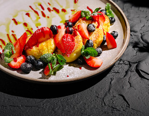 Delicious cottage cheese pancakes dessert featuring strawberries and blueberries on a dark plate