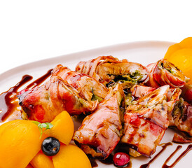 Delicious grilled meat rolls with herbs and fruits on a white plate