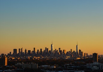 Fototapeta premium Vibrant Sunset City Skyline Silhouette Against an Orange and Blue Sky
