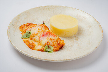 A flavorful cheese-topped entrée paired with a smooth, creamy side, beautifully arranged on a plate