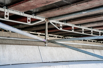 Stadium understructure detail with scaffolding and steel beams supporting concrete seating, construction engineering framework, architectural infrastructure strength, durable building stability closeu
