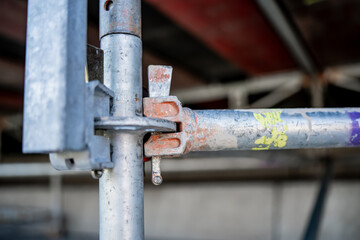 Metal scaffolding clamp joint in stadium understructure, close view of fastening mechanism with steel pipes, construction detail of secure framework, architectural engineering strength and support sys