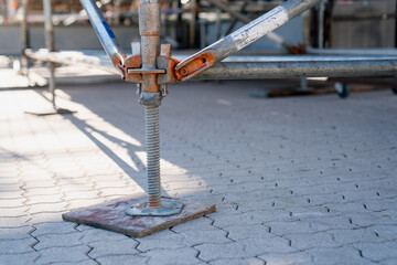 Scaffold base jack with square plate on ground, structural support element used in staging,...