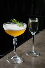 Two stylish cocktails sit on a polished counter, showcasing vibrant colors and elegant glassware