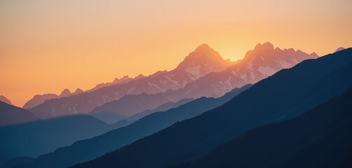Obraz premium Serene mountain landscape at sunset, with layered peaks silhouetted against a dramatic, glowing sky, highlighting nature's majestic beauty.