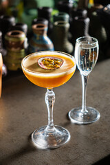 A vibrant mixed drink with passion fruit awaits beside a sparkling glass, inviting taste