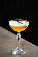 A golden cocktail with a cinnamon garnish sits elegantly, evoking warmth