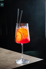 Bright red cocktail with citrus slices sits on a chic bar top, inviting relaxation and enjoyment