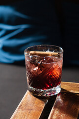 A vibrant drink sits elegantly on a wooden surface, showcasing deep red tones with a cinnamon stick