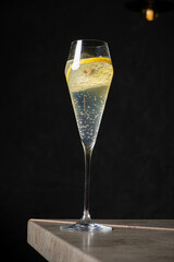 A refreshing cocktail with bubbles, garnished with a lemon slice, captured in dim lighting