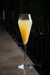 A vibrant cocktail, blending shades of orange and yellow, elegantly catches the light at a bar