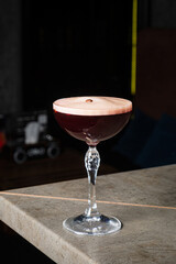 Delicate cocktail with rich color showcases craftsmanship and elegance in a dimly lit bar setting