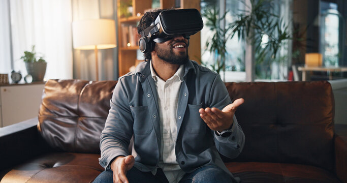 Virtual reality, happy and man on sofa in home for online gaming, metaverse and connection. Gamer, living room and person with VR headset for futuristic user experience, simulation and entertainment