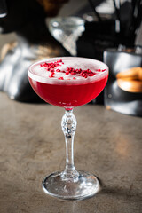 A vibrant cocktail featuring rich red hues is elegantly garnished with fruit, showcasing artistry
