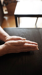 Obraz premium Elderly woman’s wrinkled hands clasped together, senior healthcare concern and aging health issues