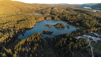 A turquoise lake in the middle of a forrest with small islands on it. Sunset in the evening. Norway (Mykland)