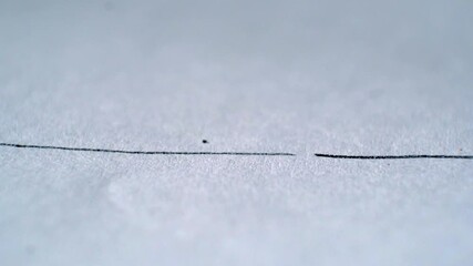 Macro close‑up of pencil drawing straight line on paper as tip suddenly breaks mid‑stroke
