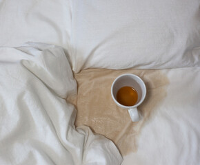 A spilled cup of tea on the bed. A cup accidentally fell on a white sheet. Bad, bad breakfast. A wet spot