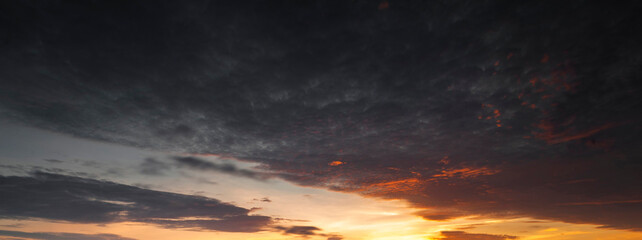 Naklejka premium A beautiful sunset sky with dramatic and colorful clouds during twilight. The vibrant gradient of orange, purple, and blue creates a peaceful and romantic atmosphere, perfect for nature backgrounds an