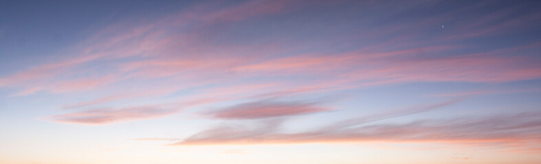 A beautiful sunset sky with dramatic and colorful clouds during twilight. The vibrant gradient of orange, purple, and blue creates a peaceful and romantic atmosphere, perfect for nature backgrounds an