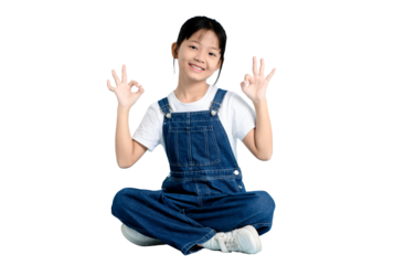 A young girl sitting cross-legged with both hands making an okay gesture and wearing a cute jumpsuit on PNG 
