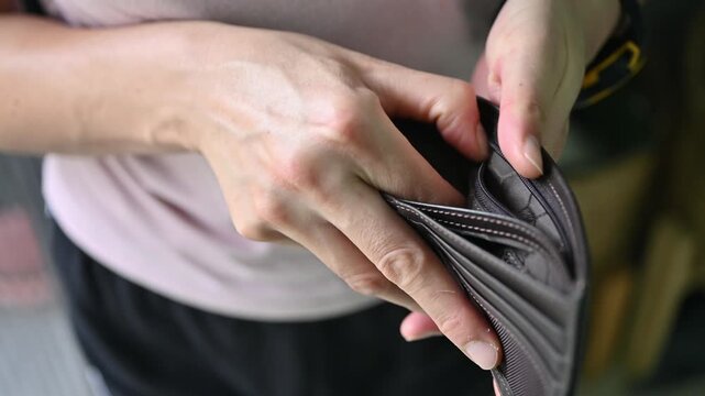 Footage of woman holding an empty wallet. Having financial problems means being unable to pay debts over the short or long term.