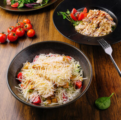 Delicious salad bowls with fresh tomatoes on a wooden table setting