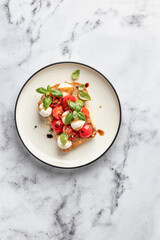 Caprese sandwich or toast with mozzarrella balls, cherry tomatoes, olive oil and fresh basil leaves top view, isolated. Healthy vegetarian breakfast. White marble background