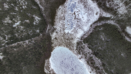 Aerial View of Partially Frozen Lake Surrounded by Snowy Forest