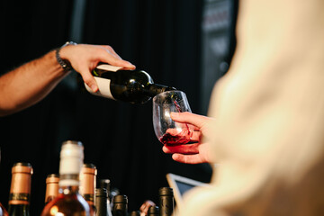 A Waiter Pouring Red Wine from a Bottle into a Glass at a Party
