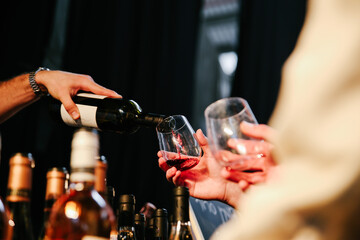 A Waiter Pouring Red Wine from a Bottle into a Glass at a Party