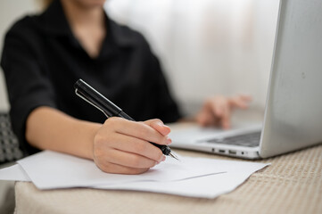Close up of asian businesswoman or office worker holding a fountain pen over paper at working table.