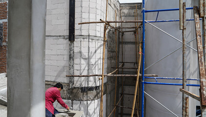 Worker working on the construction site with scaffolding and cement mortar