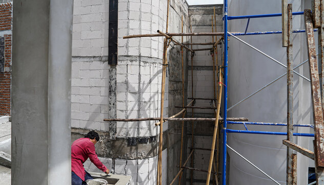 Worker working on the construction site with scaffolding and cement mortar