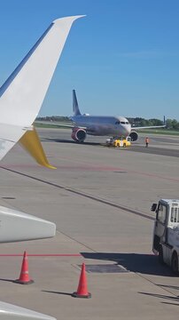 Aircraft towing across runway by pushback tug at airport. Airplane pulling forward with help from ground tow vehicle. Jet moving on tarmac guided by airport push unit