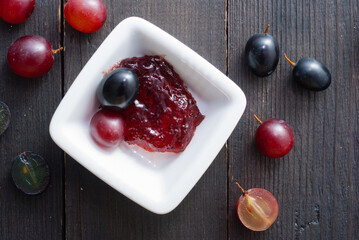 grape jelly and red grapes on black wood table
