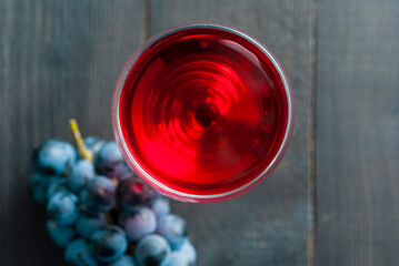 glass of red wine and grapes on black wood table background
