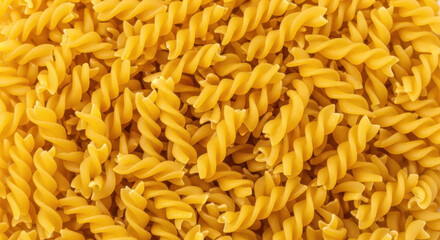 Close up view of uncooked golden fusilli pasta forming a textured background
