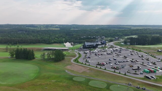Aerial of expansive golf course with manicured greens, trees, and water features in sunlight