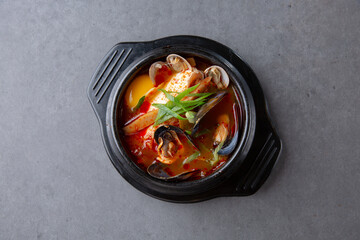 회색 배경의 한국 전통음식인 해물순두부찌개 Korean traditional food with gray background, seafood and soft bean curd jjigae