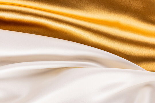 Luxurious satin fabric background in gold and ivory tones