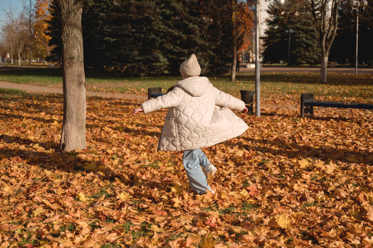 Child enjoying a carefree autumn walk among colorful leaves