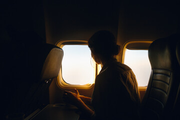 Passenger gazing out airplane window during sunset