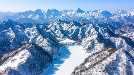 Obraz premium Snow-covered mountains and valleys stretch across the landscape, showcasing a serene winter scene ideal for travel articles, winter sports promotions, or nature-themed designs,