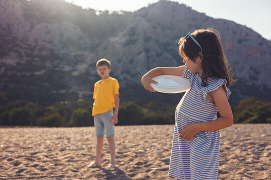 Children playing with frisbee on a sunny beach day