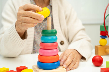 Asian elderly woman playing enhancing skill board game.